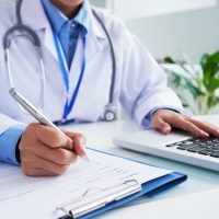 maos-da-medica-irreconhecivel-escrevendo-no-formulario-e-digitando-no-teclado-do-laptop_1098-20374